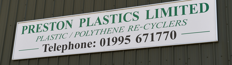 A white sign on the side of a green warehouse wall. The sign reads 'Preston Plastics Limited. Plastic/Polythene Re-cyclers. Telephone: 01995 671770'