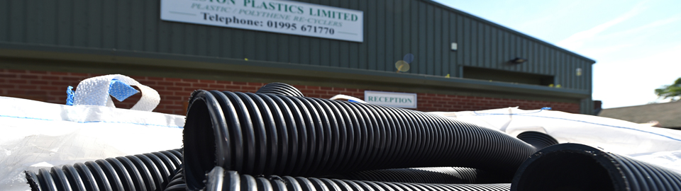 Black plastic tubing in a bag in front of the Preston Plastics Limited warehouse.